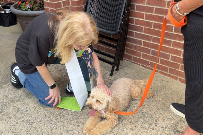 The Rev. Betsy Singleton Snyder offers a blessing to Julia Sugarbaker, a mini goldendoodle, at Pinnacle View United Methodist Church in Little Rock, Ark. Snyder and co-author Gayle Fiser have written a book on how churches can start successful pet ministries. Photo from video by Lilla Marigza, UM News.