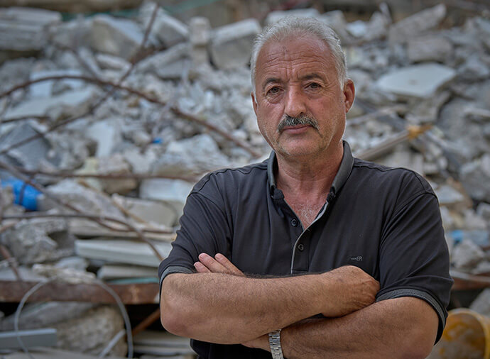 Fakhri Abu Diab stands in front of his demolished home in Silwan, a neighborhood of East Jerusalem. Israeli forces tore down his home to make way for a biblical theme park. The destruction is part of the expansion of Jerusalem and nearby settlements. Nearby Wadi Foquin has also lost farmland and homes to the settlement expansion. File photo by Paul Jeffrey.