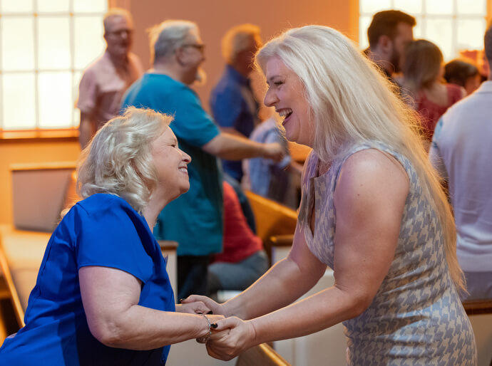 Glenda Gladden (left) and Sophie Dukes greet one another during worship at Glendale United Methodist Church.