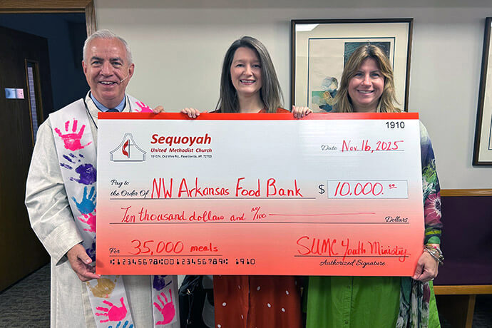 The Rev. Lindsey Russell (center) accepts a donation for the Northwest Arkansas Food Bank, where she serves as senior manager of programs. The United Methodist deacon said working in extension ministry allows her to model Christianity to people who might never enter a church. Photo courtesy of the Rev. Lindsey Russell.