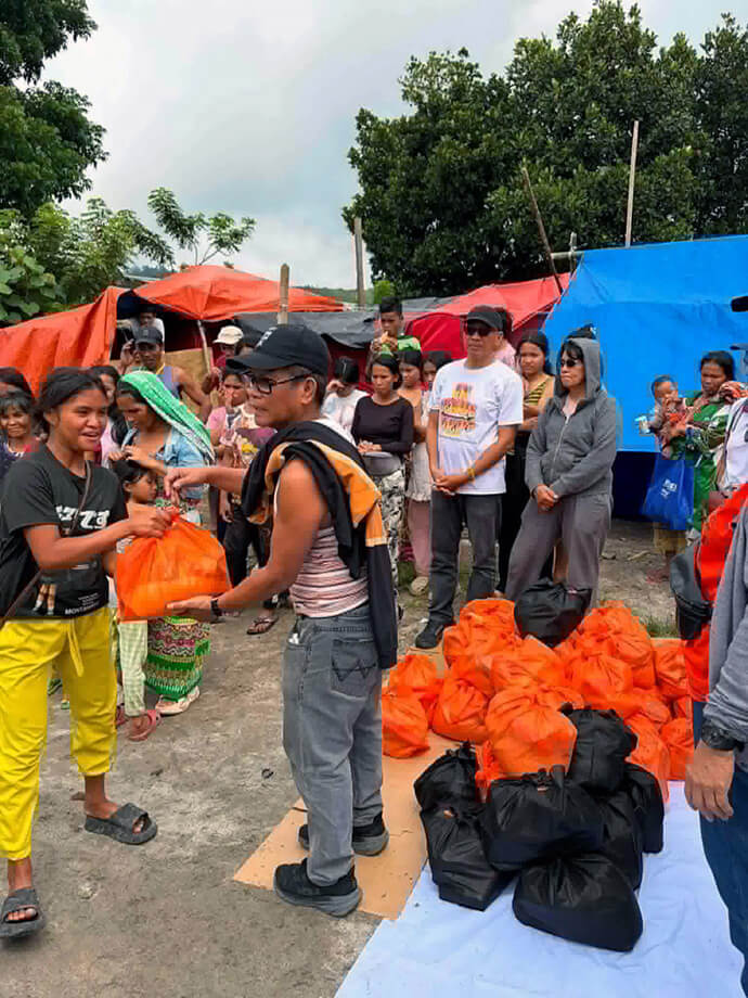 Erwin Hyman N. Mari, outreach committee chairperson at Central United Methodist Church in General Santos City (center in black hat), distributes relief supplies in Sarangani province, Philippines, as the Rev. Jonathan R. Ulanday (in white shirt) look on. Ulanday, administrative pastor of Central United Methodist, said the relief missions have enabled affected communities to regain confidence and hope amid devastation. Photo courtesy of the Rev. Jonathan R Ulanday. 