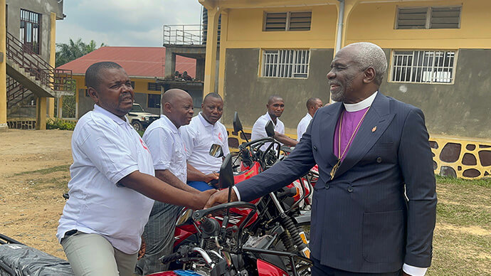 The Rev. Baukwaga Kanja Evariste, Punia 2 District superintendent, receives a handshake and congratulations from Bishop Antoine Tambwe Kalema during the official presentation of his motorcycle in Kindu, Congo. Evariste traveled nearly 250 kilometers on severely damaged roads to attend the Eastern Congo Annual Conference. Photo by Chadrack Tambwe Londe, UM News. 