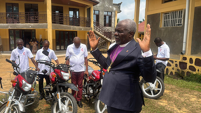 Bishop Antoine Tambwe Kalema raises his hands to pray and bless district superintendents and their new motorcycles in Kindu, Congo, in the Maniema Province. The bishop purchased the bikes with his own money at a cost of about $22,000. The donation brings to life Kalema’s initiative titled “Cast the Net on the Other Side,” which promotes building first with the resources of the episcopal area before seeking outside support. Photo by Chadrack Tambwe Londe, UM News.