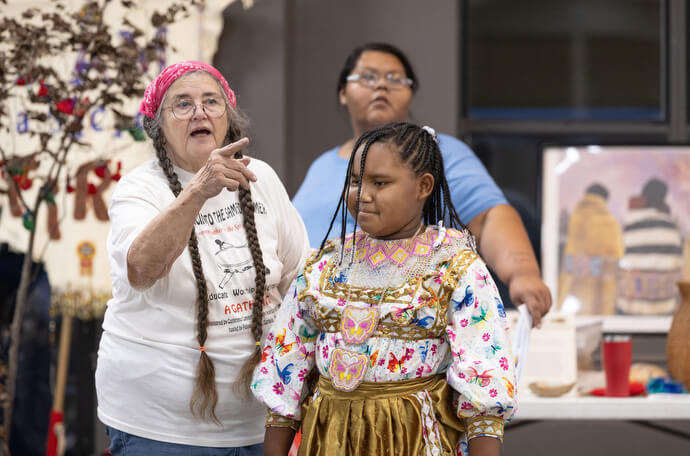 Mary T Newman highlights multiple generations participating in the Native Moccasins Rock gathering. Standing with her is Amaria Brooks. At rear is Angel Bell. 