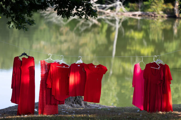 Red dresses and tops symbolizing missing and murdered Indigenous women hang along the shore of Lake Benson during Native Moccasins Rock in Bon Aqua, Tenn. 