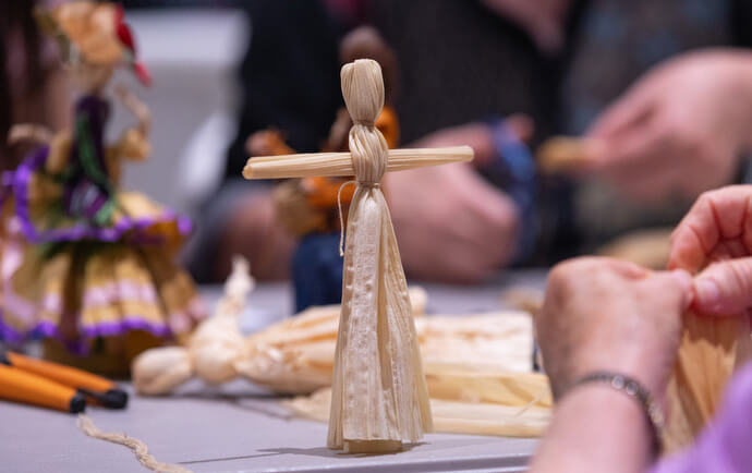 Workshop participants learn to make corn-husk dolls at Native Moccasins Rock. Photo by Mike DuBose, UM News. 