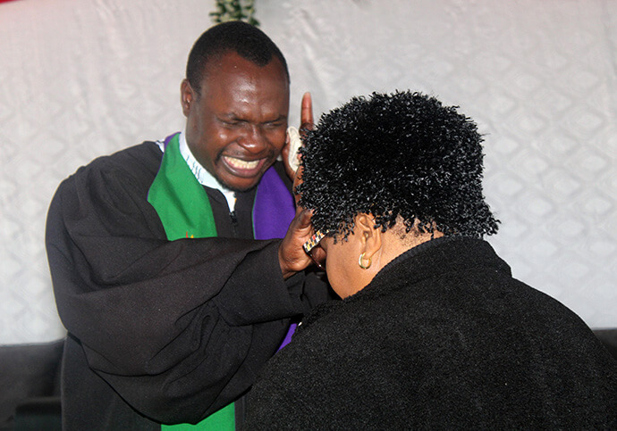 The Rev. Cosmas Chafanza, pastor-in-charge of Magamba Circuit, prays over a church member during worship. The circuit’s hospitality has been a key factor in growth, church leaders say. Photo by Kudzai Chingwe, UM News.