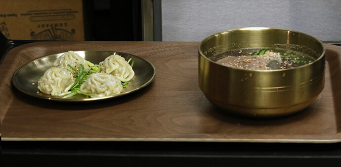 Mandu (Korean dumplings) and a bowl of naengmyeon (Korean cold noodles) wait to be served from the kitchen at The Table Korean Cuisine, which is housed inside Grace United Methodist Church. People seeking authentic Korean food and fellowship in the Kansas City area pack the restaurant on Friday evenings. Photo by the Rev. Thomas E. Kim, UM News.