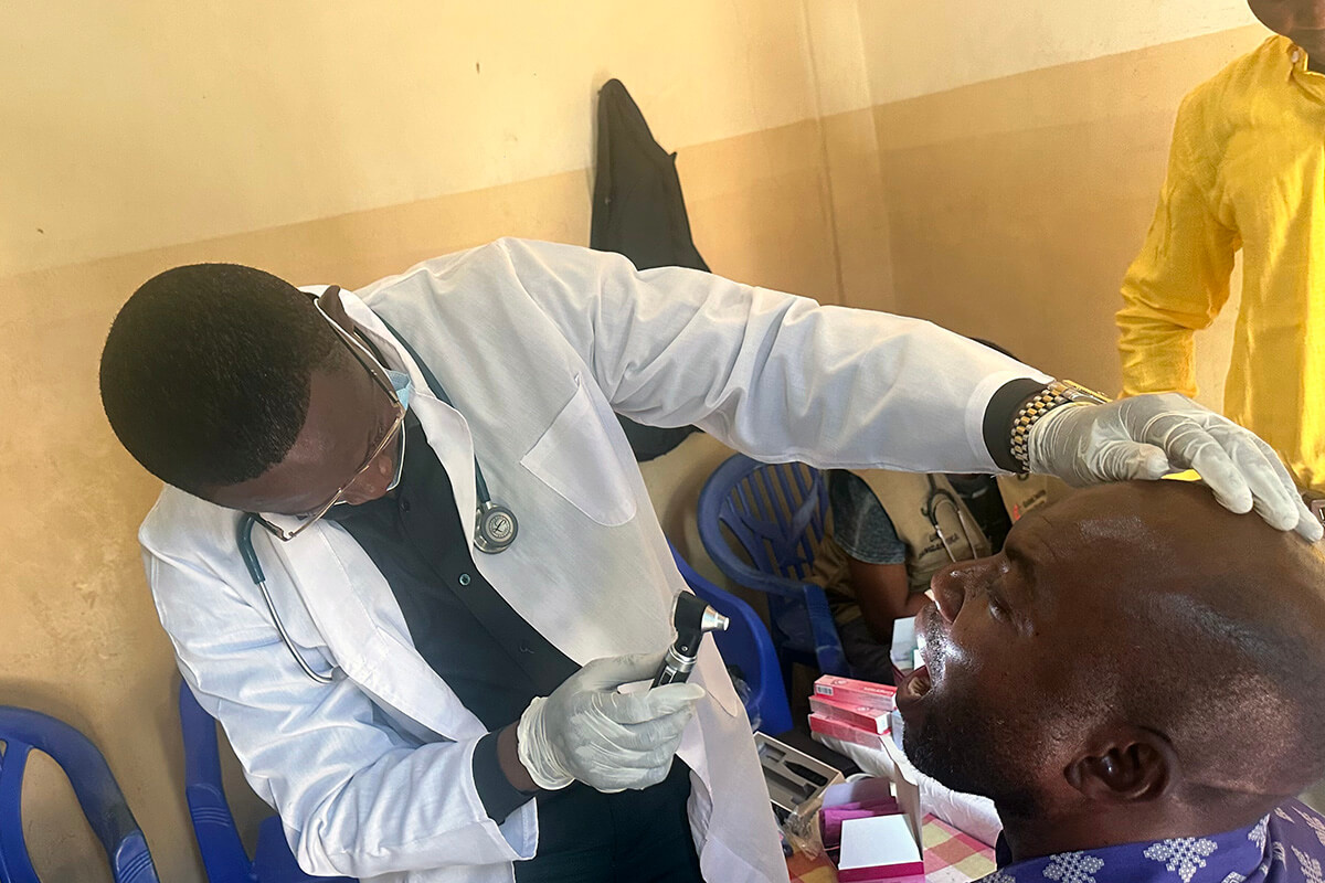 Dr. Élisée Kilumba, coordinator of medical ministries for the Tanganyika Episcopal Area, examines a patient’s throat during a clinic session in Kalemie, Congo. More than 600 church members and leaders in Manono and Kalemie were treated during United Methodist annual conferences in the southeastern region of the country. Photo by Chadrack Tambwe Londe, UM News.
