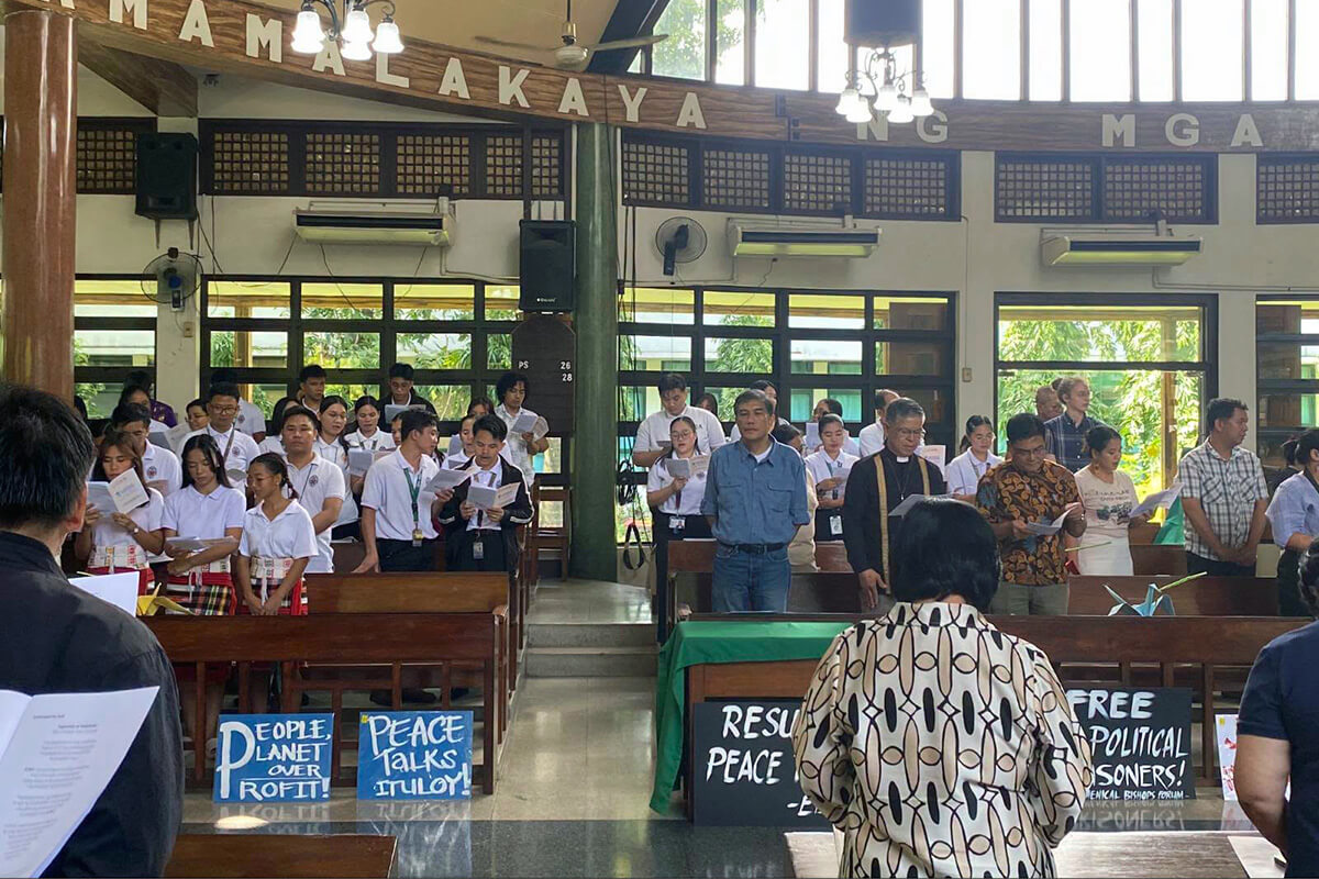 Mervin Toquero, (center in blue polo shirt), a United Methodist and leader of the National Council of Churches in the Philippines, joins with other ecumenical church leaders, peace advocates and others at the 2026 Day of Prayer for Just Peace that took place in Quexon City. Those gathered raised concerns over the social and environmental risks of the U.S.-led Pax Silica initiative. Photo courtesy of the National Council of Churches in the Philippines.