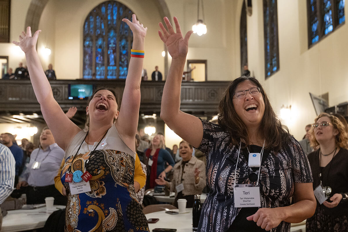 Ashlee Vitz (left) and Teri Watanabe raise their arms in praise during opening worship Oct. 21 at the United Methodist Leadership Gathering at Knox United Church in Calgary, Canada. The event, which continues through Oct. 24, brings lay and clergy from around the world together to imagine a new future for The United Methodist Church.  Photo by Mike DuBose, UM News.