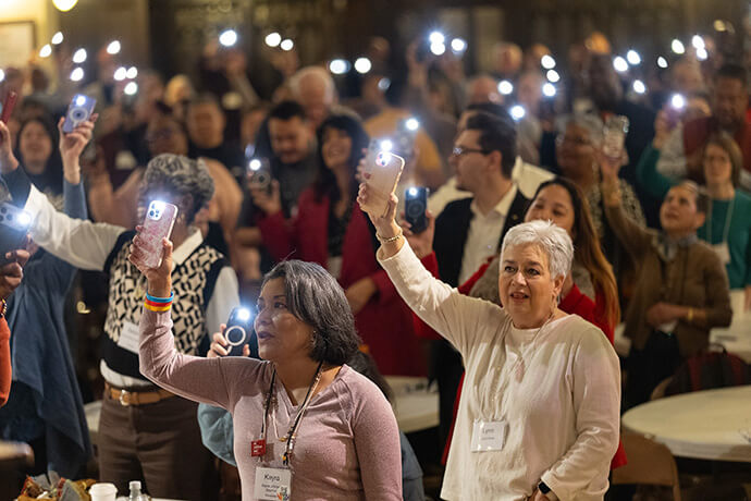 Kayra Johnson (center, left) and Lynn Mote join with hundreds of others attending the United Methodist Leadership Gathering in waving their glowing cell phones to the tune of “This Little Light of Mine,” at the close of morning worship on Oct. 23. Photo by Mike DuBose, UM News.