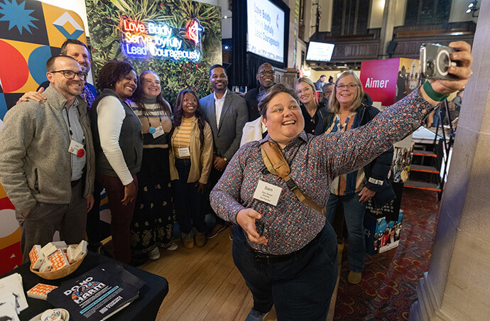 Sam Blewis makes a group photo in front of a booth promoting The United Methodist Church’s vision statement to “ love boldly, serve joyfully, and lead courageously,” on Oct. 23 during the United Methodist Leadership Gathering in Calgary, Canada. Photo by Mike DuBose, UM News.