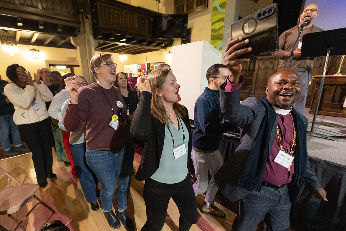 Bishop Ande Emmanuel of Nigeria (right) leads a celebratory dance line to the song “We Are Marching in the Light of God” at the close of the United Methodist Leadership Gathering on Oct. 24 at Knox United Church in Calgary, Canada. After long hours of small-group discussion, Leadership Gathering participants revealed their recommendations for The United Methodist Church yet to be. Photo by Mike DuBose, UM News.