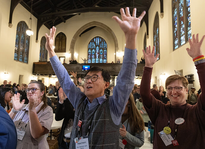 The Rev. Heecheon Jeon (center) raises his hands in praise at the conclusion of the United Methodist Leadership Gathering on Oct. 24 at Knox United Church in Calgary, Canada. He is joined by Rachel Shipley Blackwell (left) and the Rev. Anne Detjen. Photo by Mike DuBose, UM News.